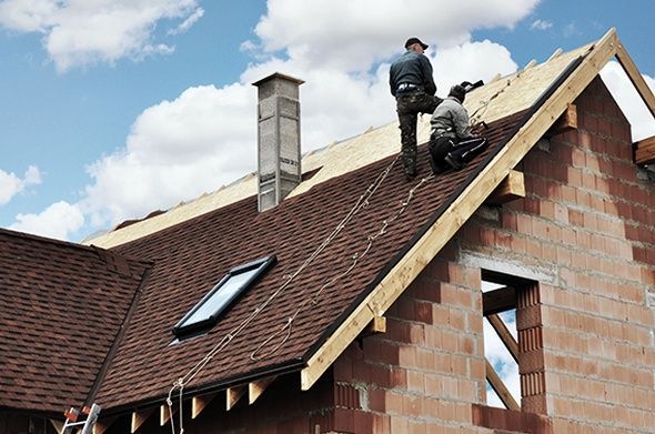 Two men are working on the roof of a house.