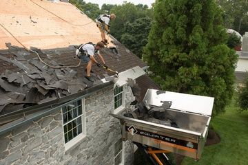 Two men are working on the roof of a house.