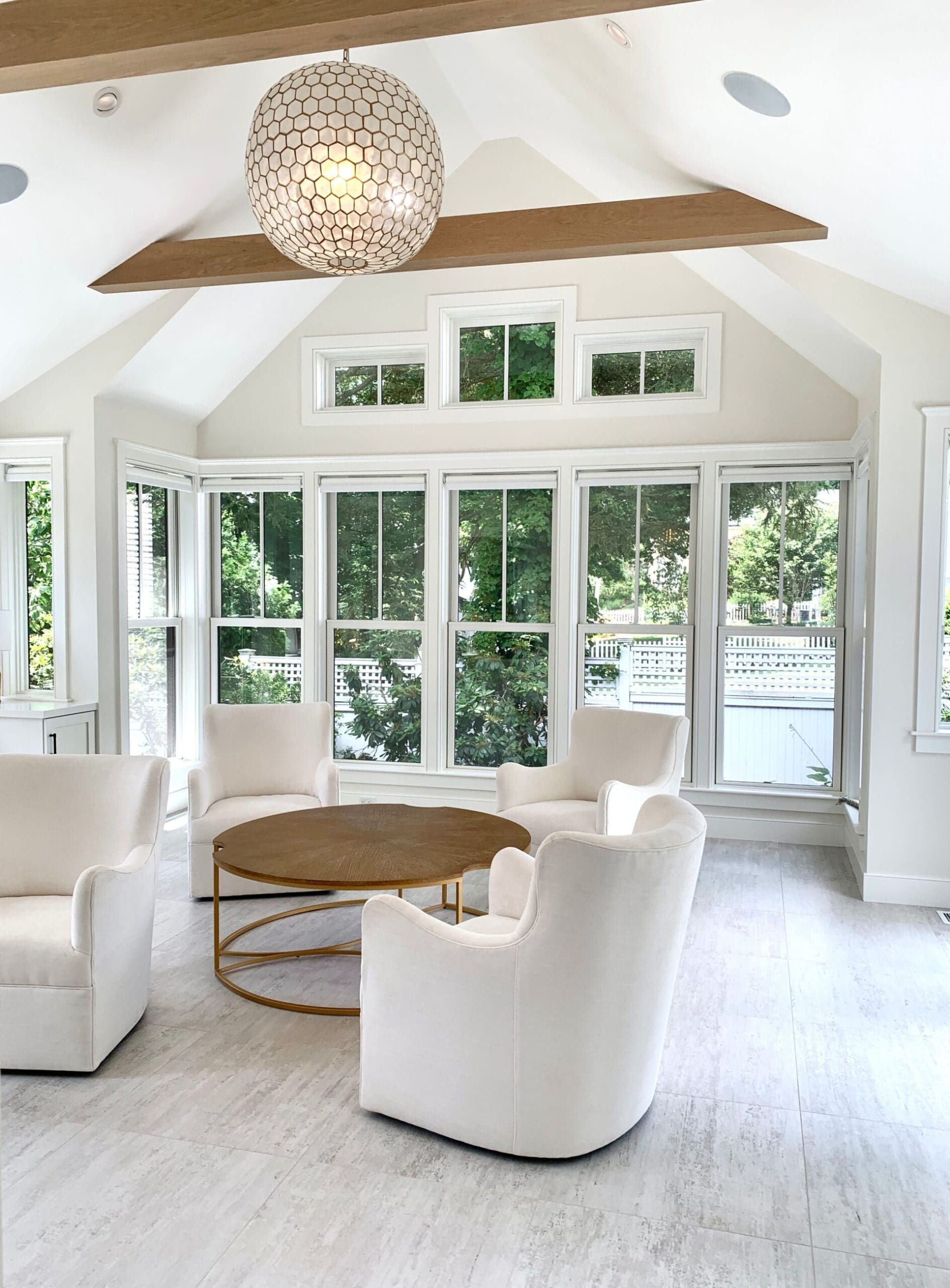 A living room with a lot of windows and white furniture