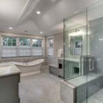 A bathroom with a tub , sink , mirror and shower.