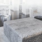 A gray ottoman is sitting on top of a gray coffee table in a living room.