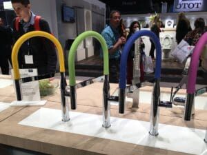 A group of colorful faucets are lined up on a counter.