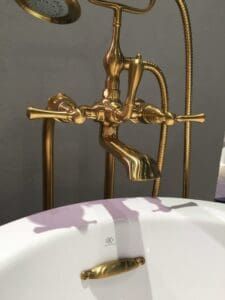 A bathroom sink with a gold faucet and shower head.