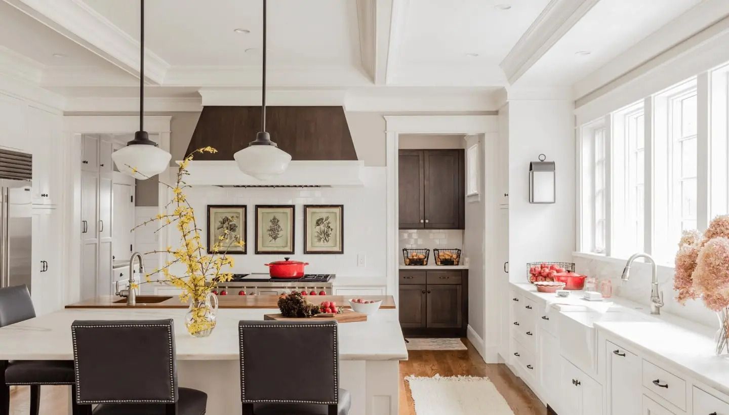 A kitchen with white cabinets and black chairs