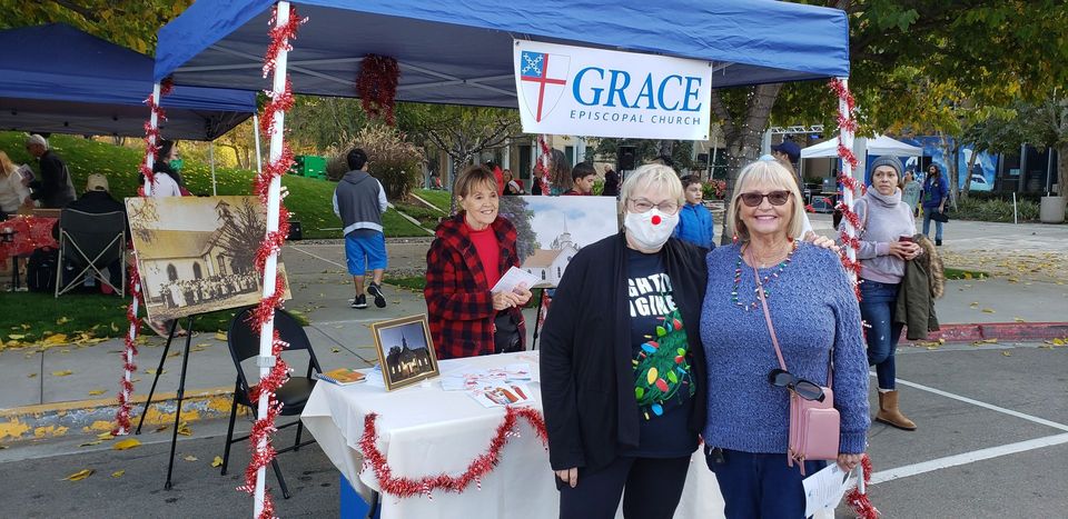 A man and a woman are standing in front of a blue tent.