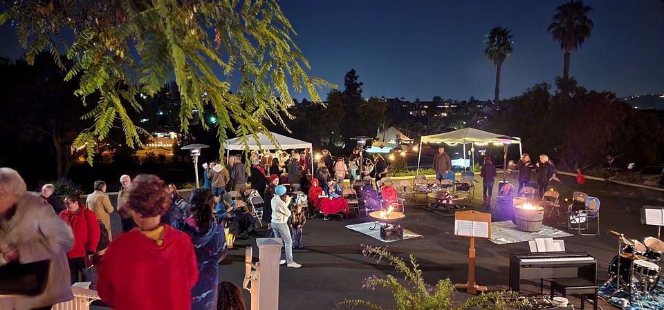 A large group of people are gathered in a parking lot at night.