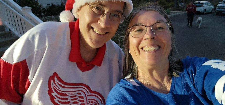 Two women wearing santa hats and sweaters are posing for a picture.