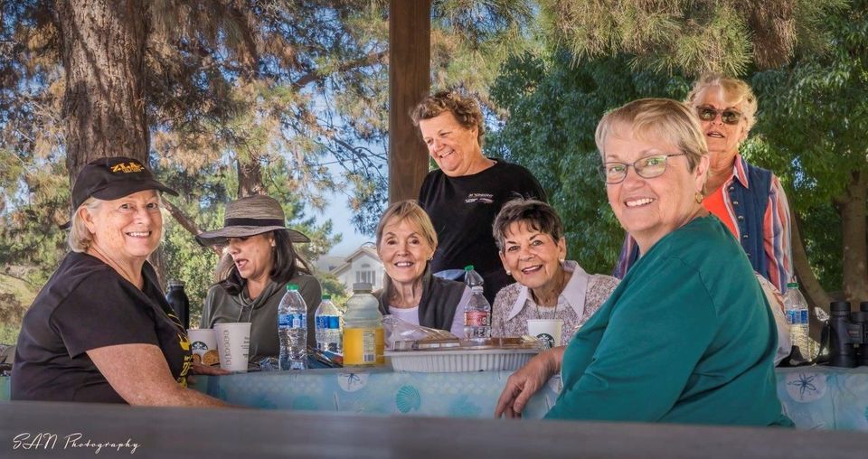 A group of women are sitting at a picnic table.