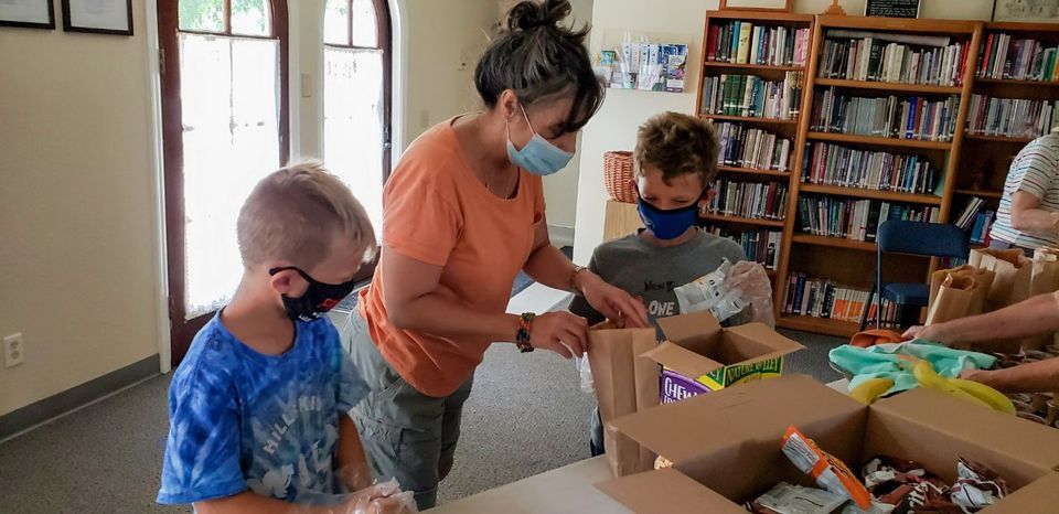 A group of people wearing face masks are standing around a table.
