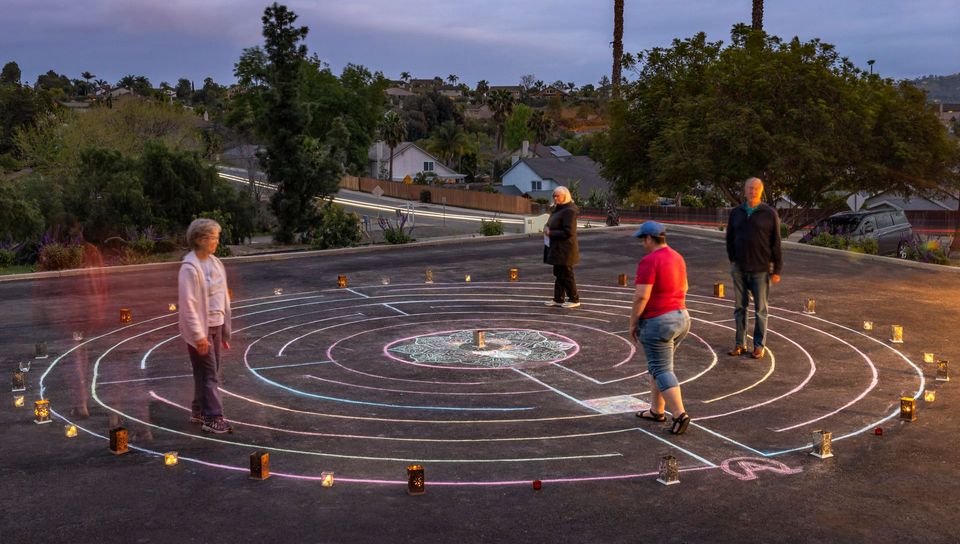 A group of people are standing around a labyrinth in a parking lot.