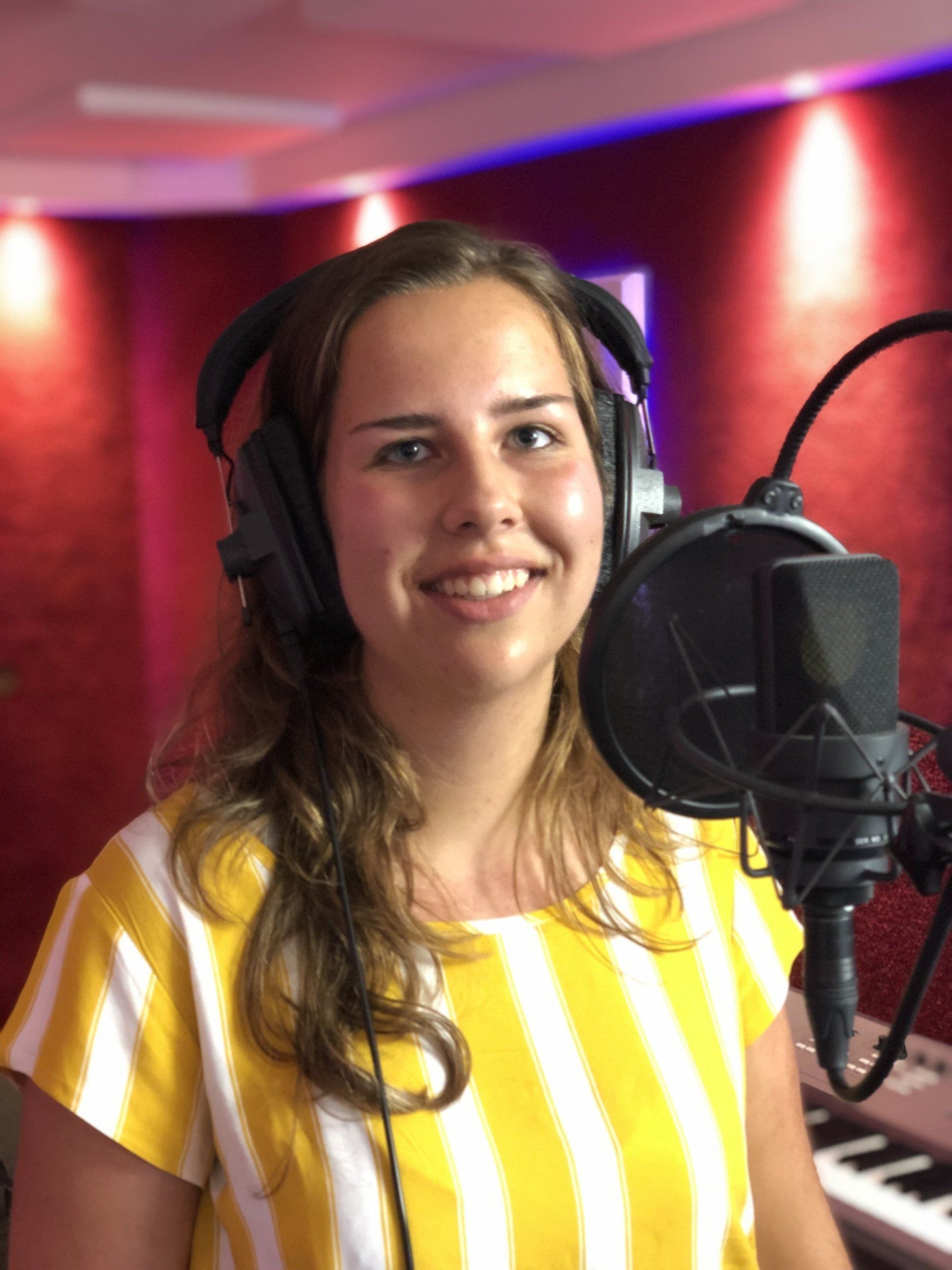 Een vrouw met een koptelefoon staat voor een microfoon