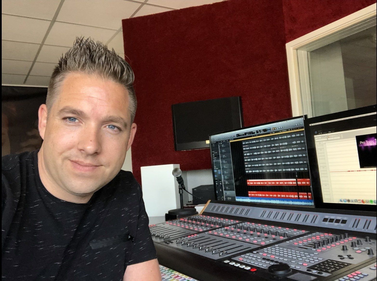 Een man in een zwart shirt zit voor een geluidsbord