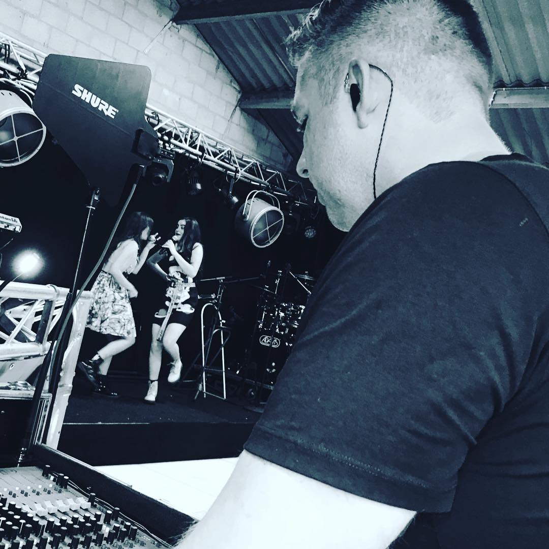 Een man met een koptelefoon kijkt naar een Shure-microfoon