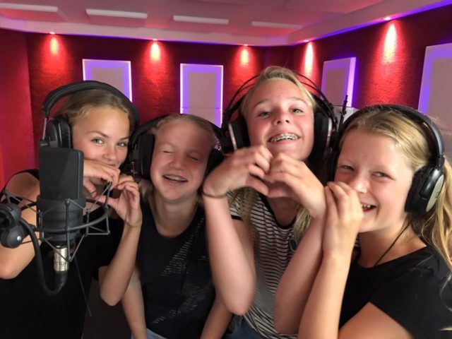 Een groep jonge meisjes met een koptelefoon en een microfoon