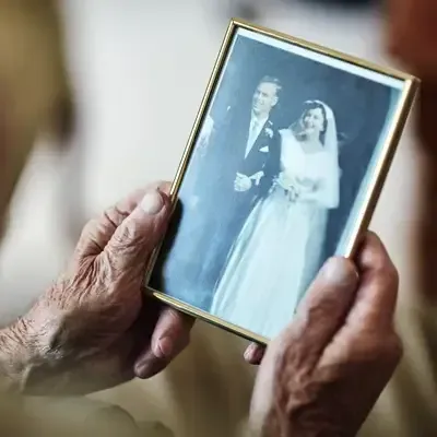 Hands holding a framed black-and-white wedding photo of a smiling bride and groom