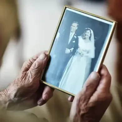 Hands holding a framed black-and-white wedding photo of a smiling bride and groom