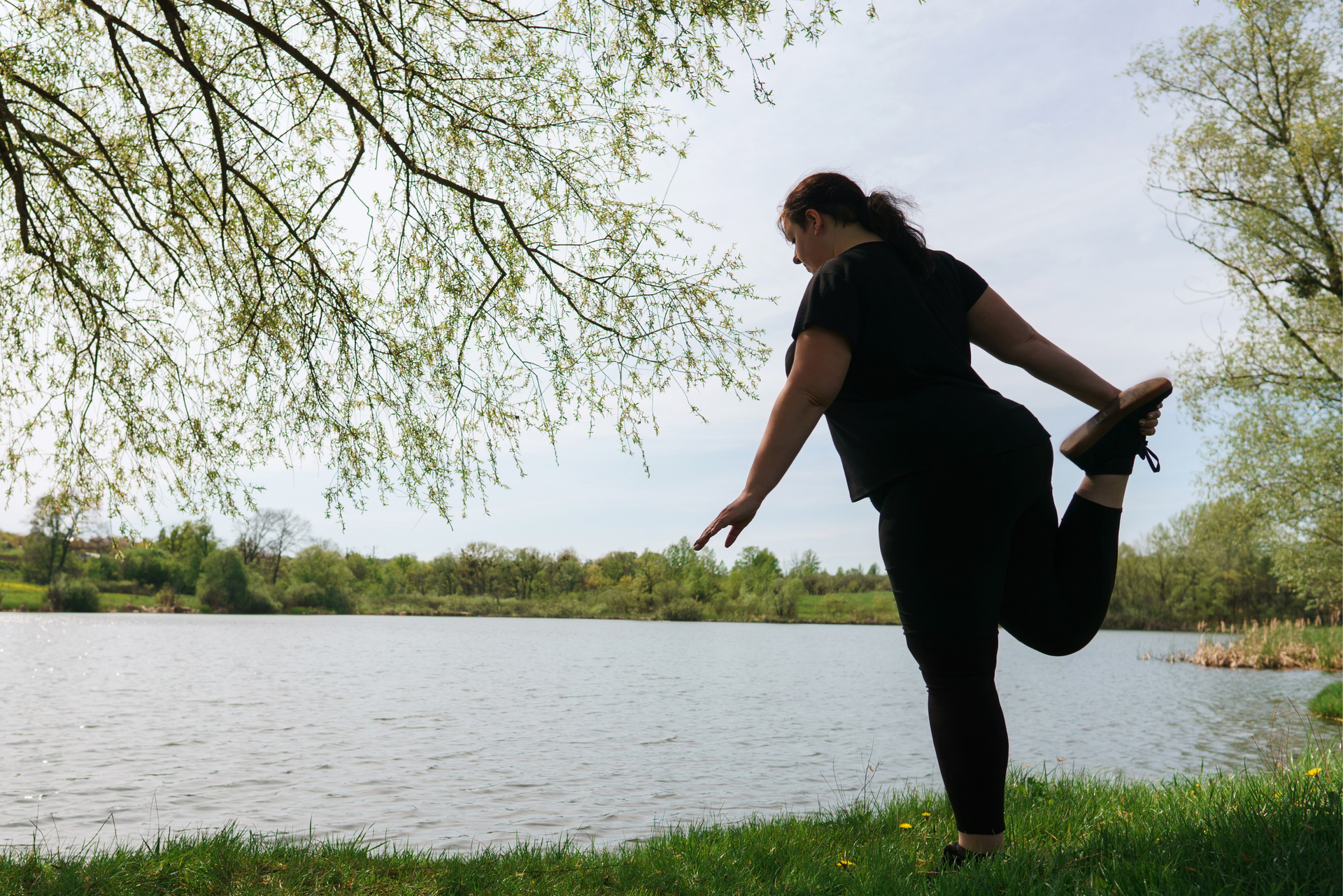A woman is stretching by a river.