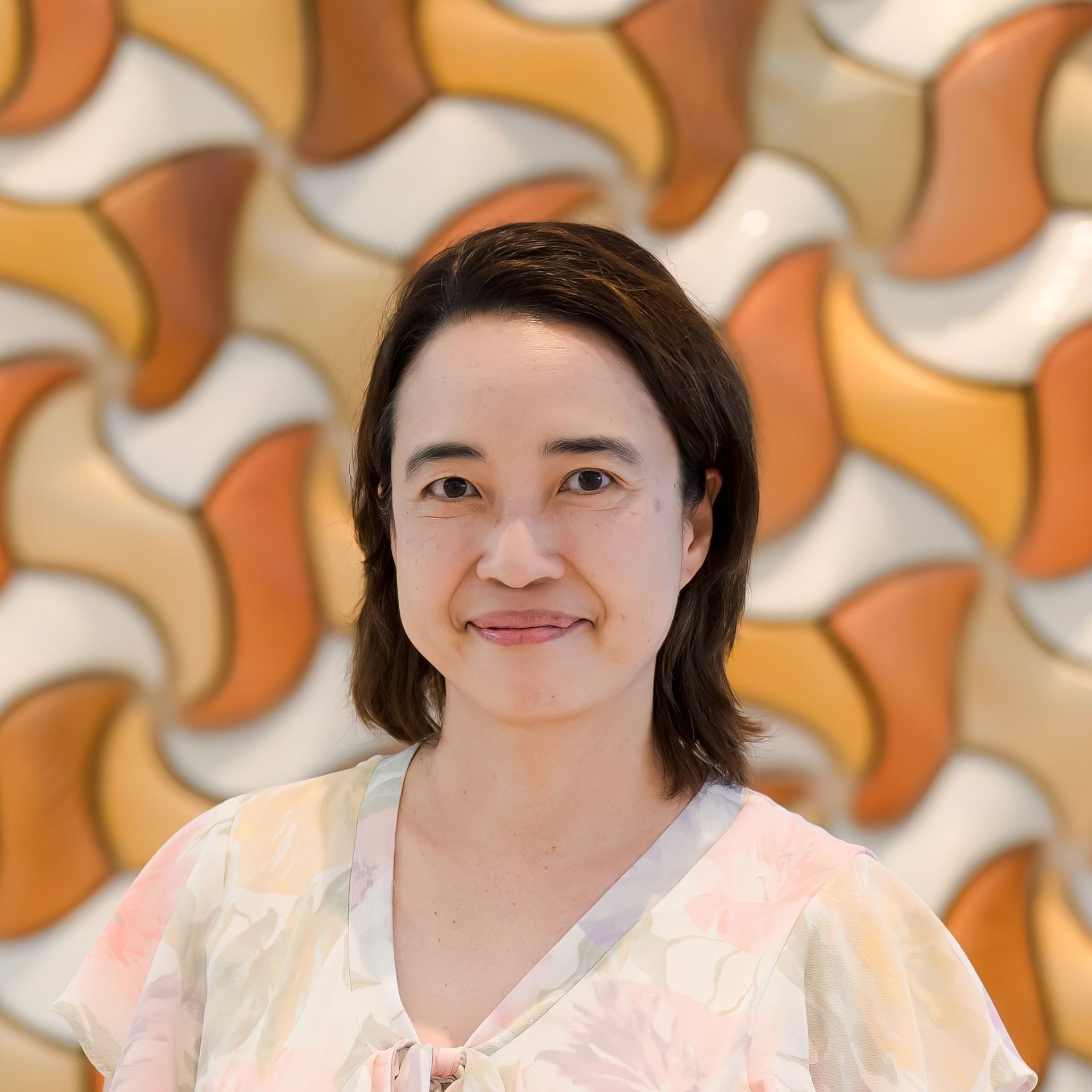 Dr Liz Wong, bariatric GP at Aurora Bariatrics, smiling in front of abstract artwork in soft tones