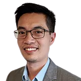 A man wearing glasses and a suit is smiling for the camera.