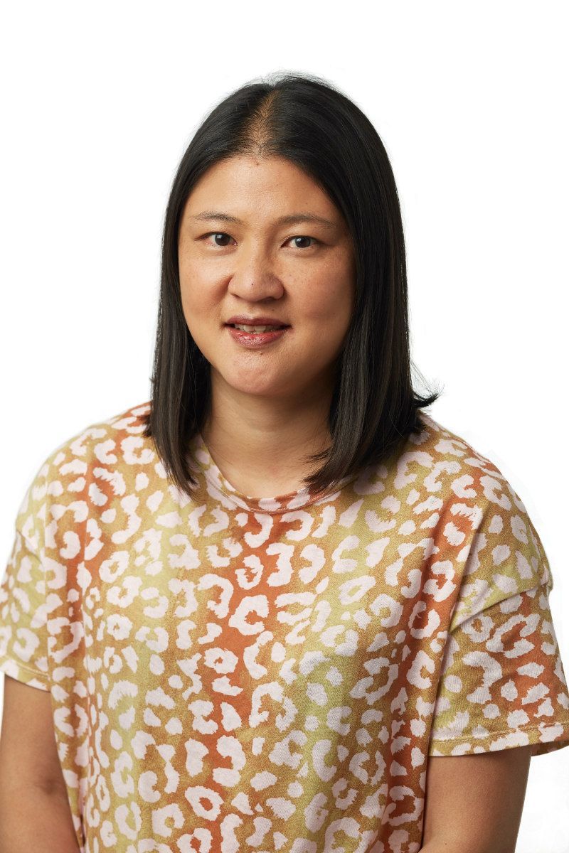 A woman wearing a leopard print shirt is standing in front of a white background.