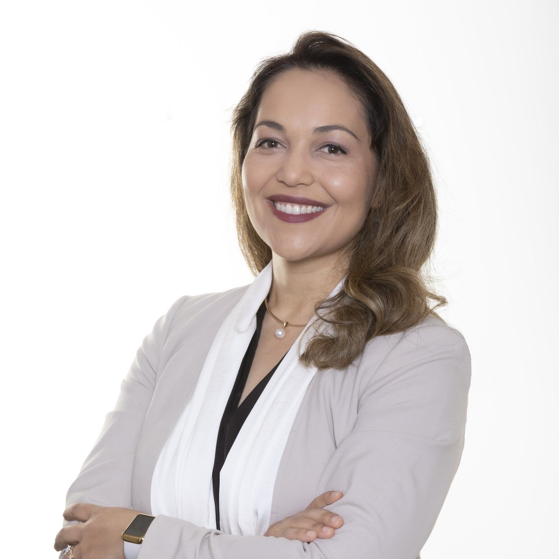 A woman in a business suit is smiling with her arms crossed