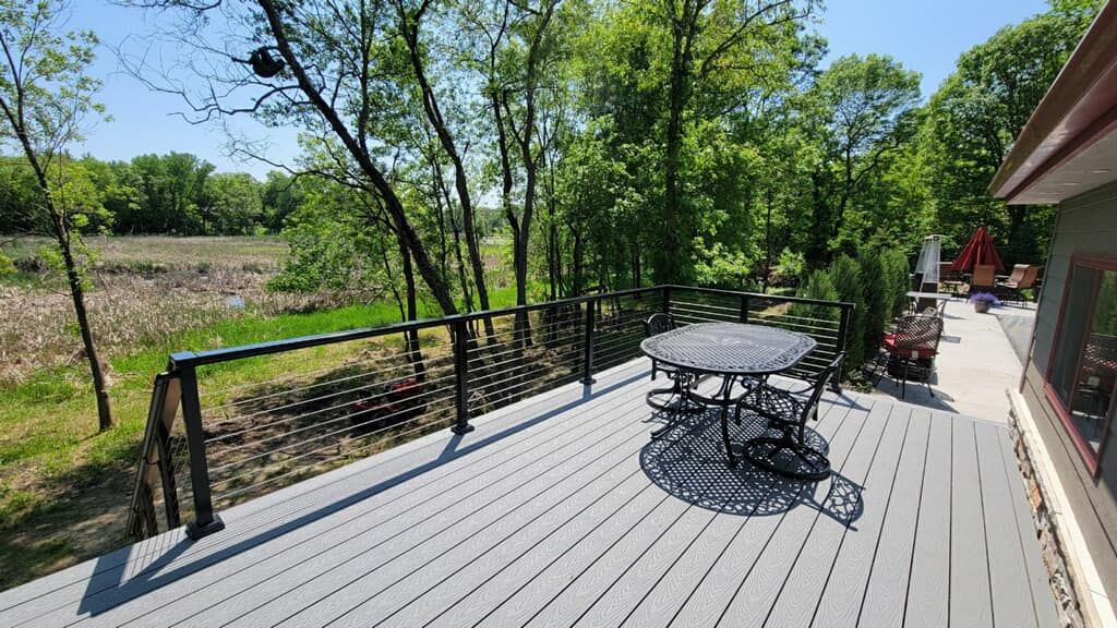 Deck with black railing and furniture overlooks a wetland area surrounded by trees.