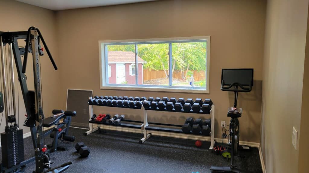 Home gym with weight racks, exercise machine, and window.