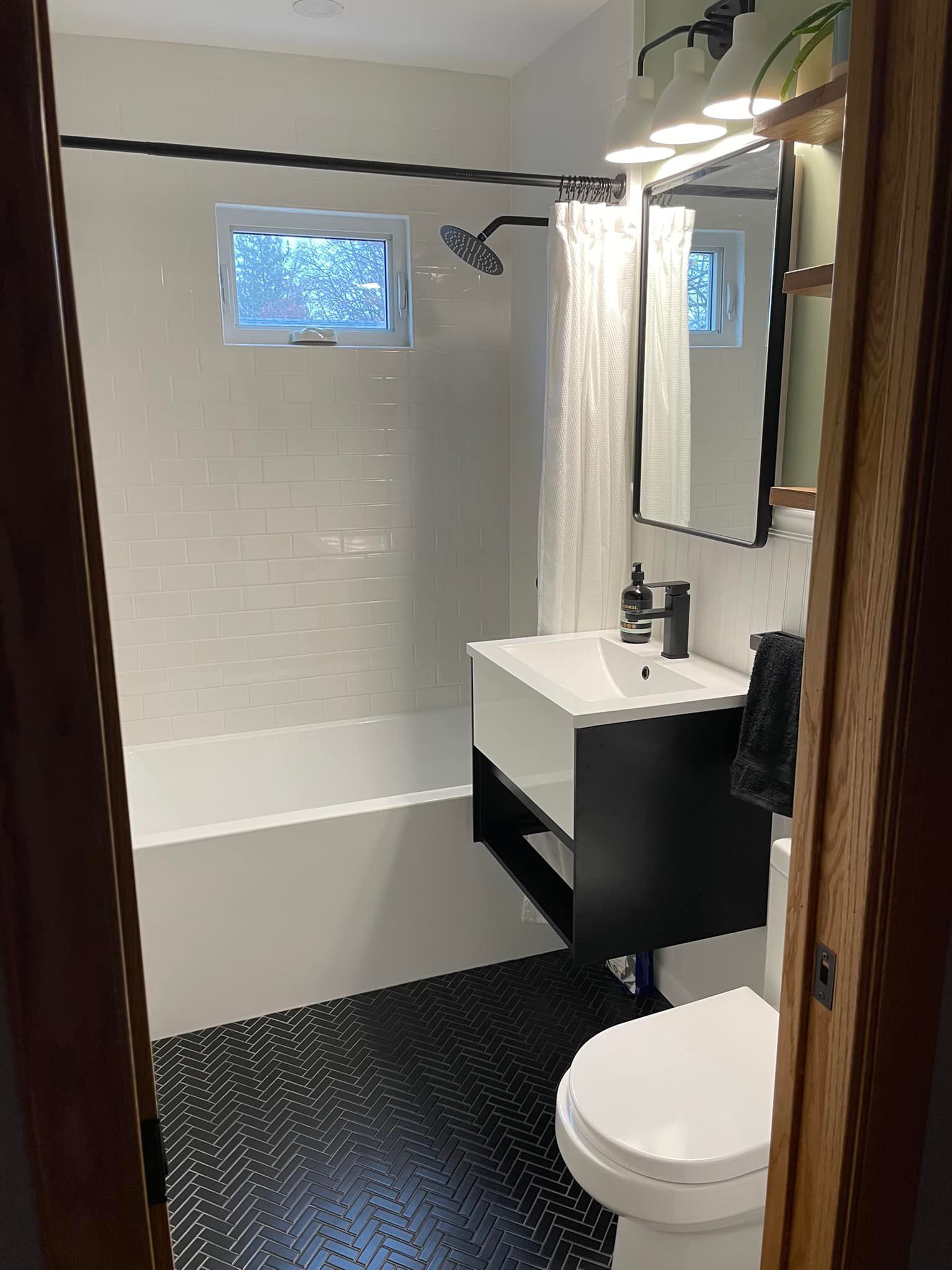 Modern bathroom with white subway tile, black vanity, and patterned black floor tile.