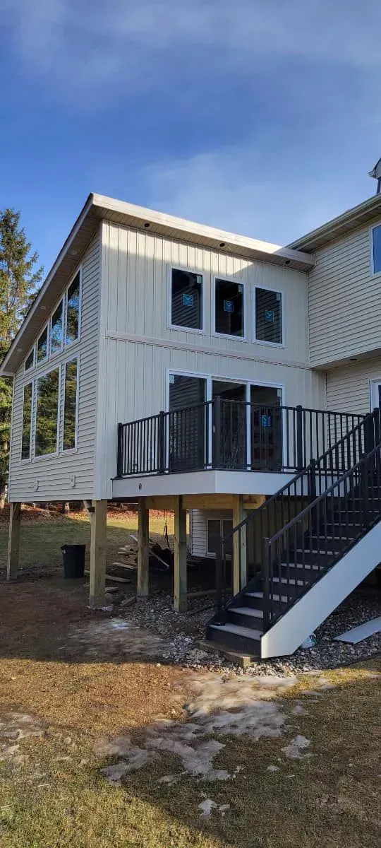 Narrow kitchen with white cabinets, black countertops, stainless steel appliances, and a tiled backsplash.