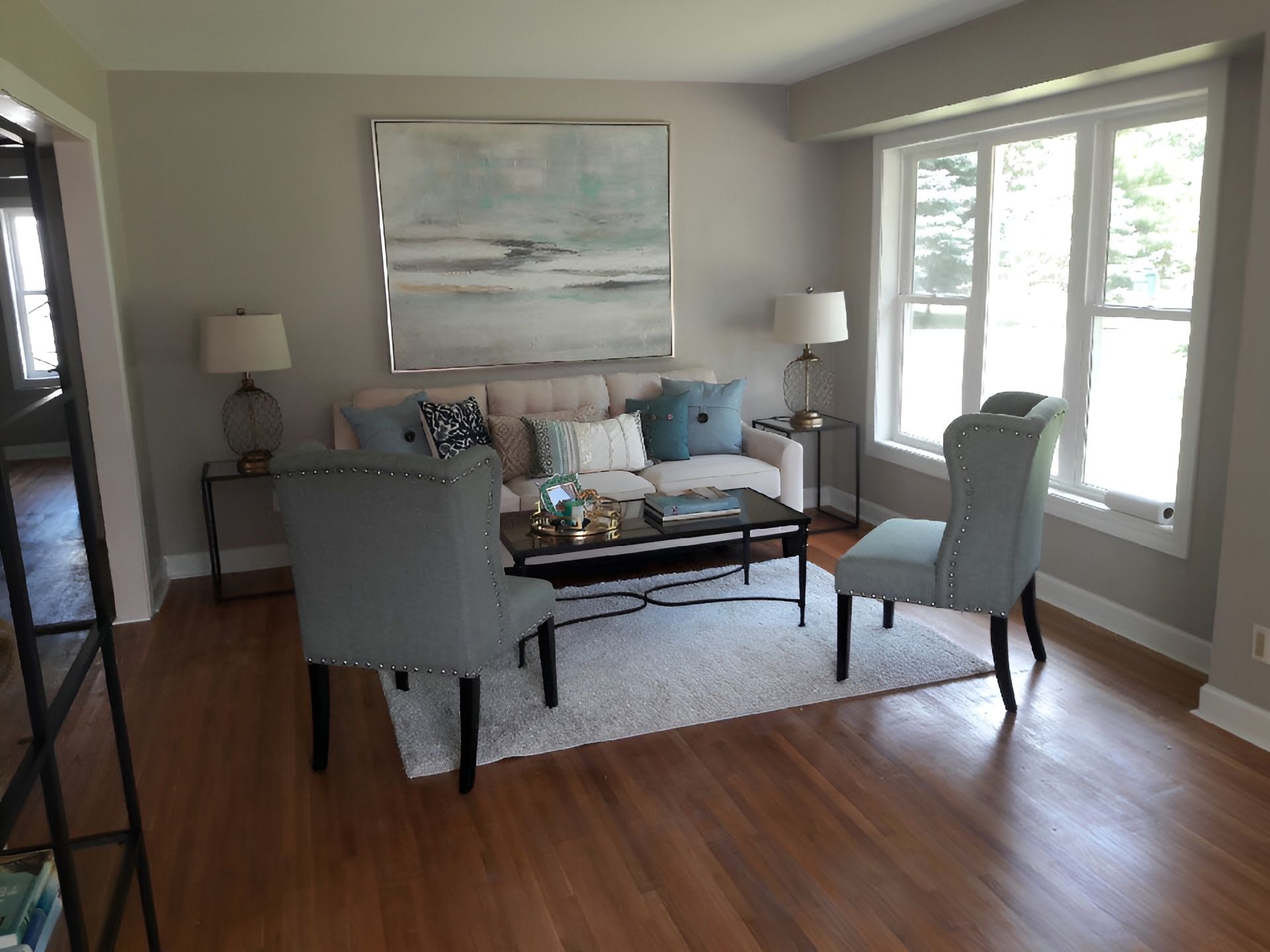 Living room with beige sofa, blue accents, artwork, and hardwood floors.