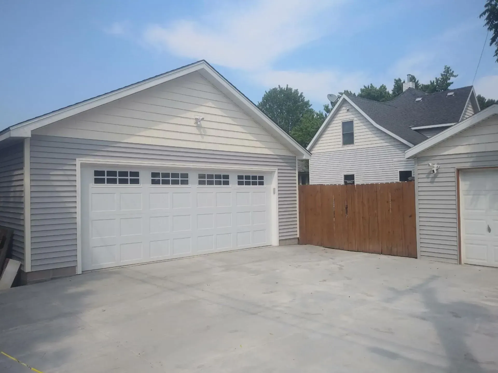 Garage with a white door, light grey siding, and a concrete driveway.
