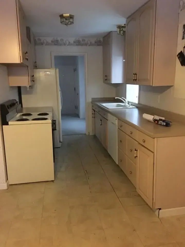 Kitchen with white appliances, light cabinets, and beige countertops and flooring.