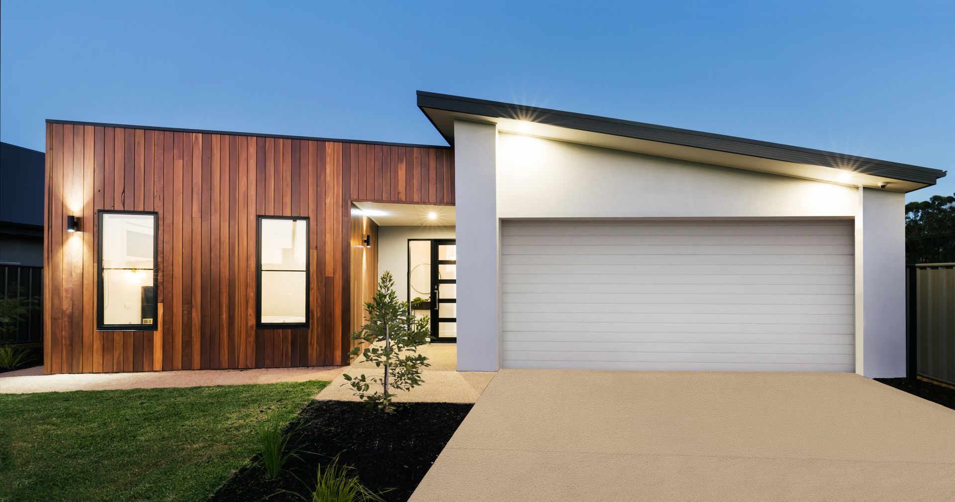 Modern Australian home at dusk with timber cladding and garage door.