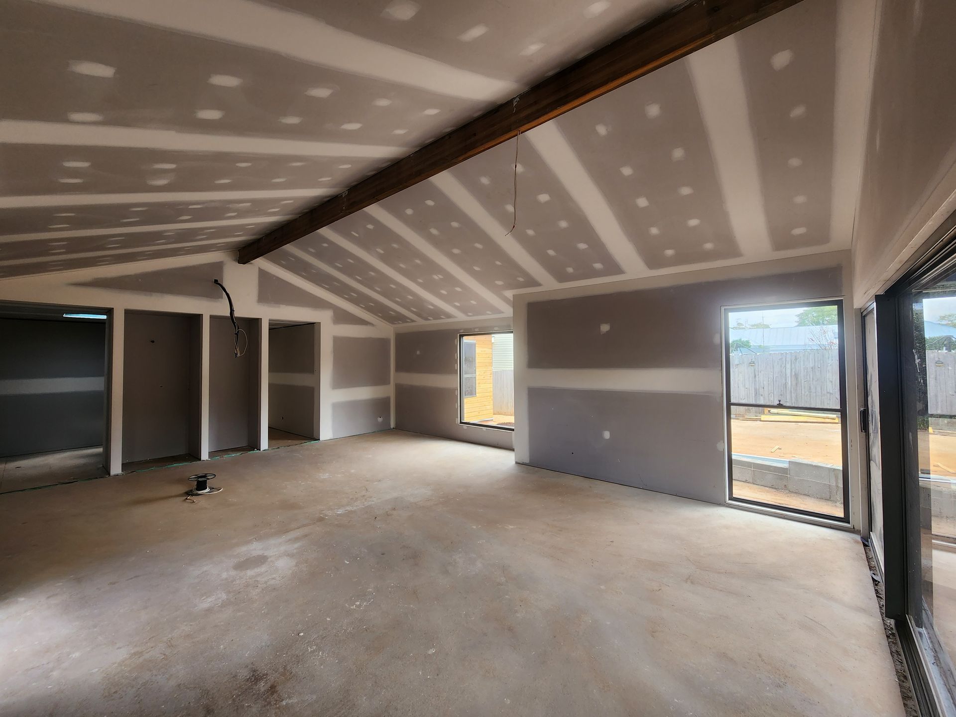 Interior of a house under construction. Drywall installed on walls and angled ceiling, unfinished concrete floor.