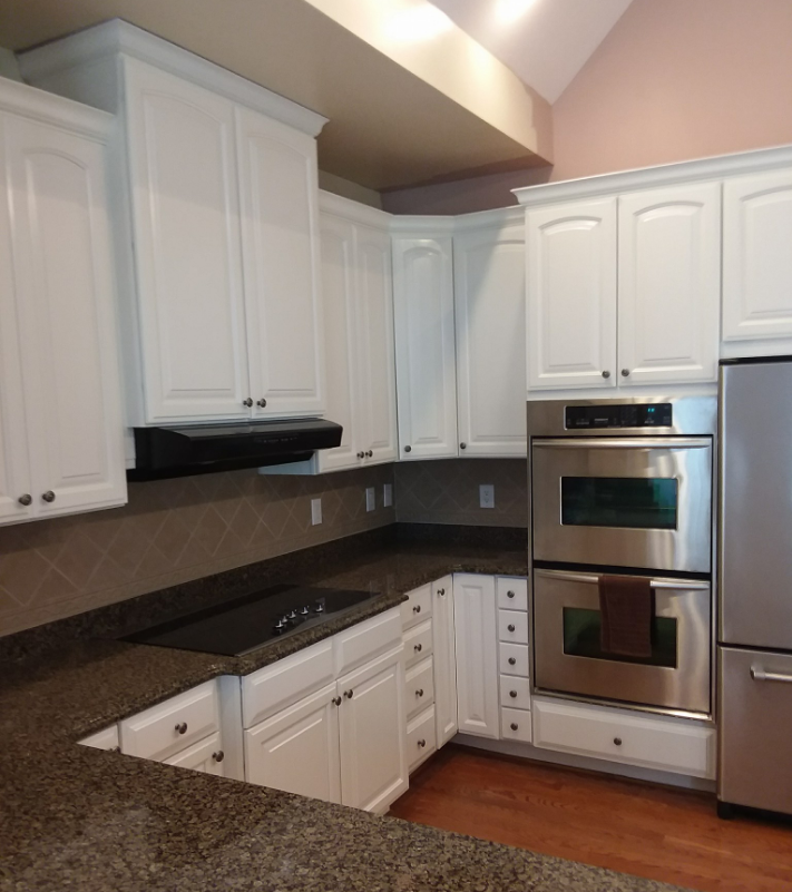 White kitchen cabinets with a dark countertop and stainless steel appliances.