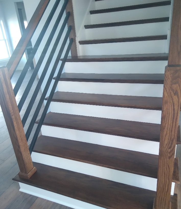 Dark wooden stairs with white risers and a metal railing. Wooden posts frame the stairs.