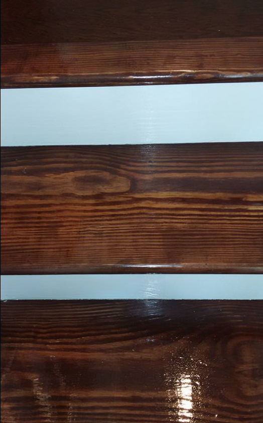 Close-up of wooden stairs with dark brown stained steps and light blue painted risers.