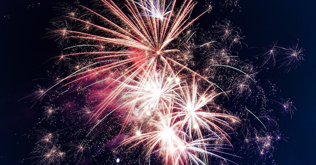 Red, white, and gold fireworks bursting in the night sky