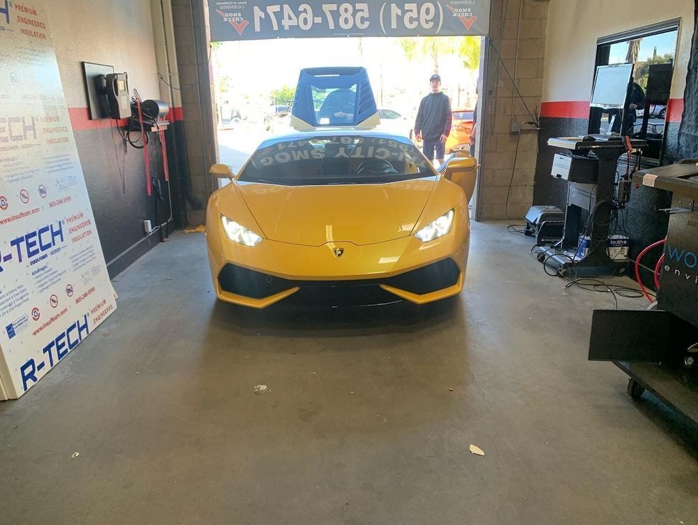 Yellow Lamborghini inside a shop, person standing near it. Shop has open door.