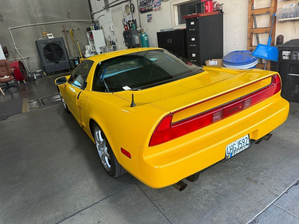 Yellow Honda NSX sports car parked inside a garage.