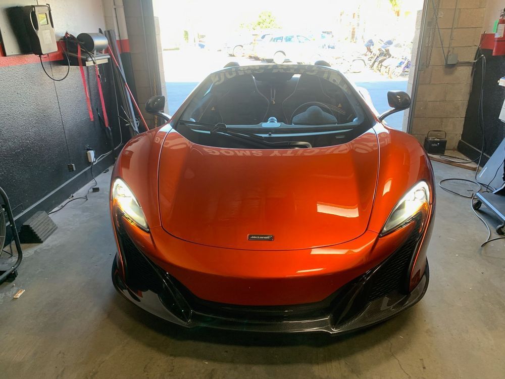 Orange McLaren sports car parked inside a garage.