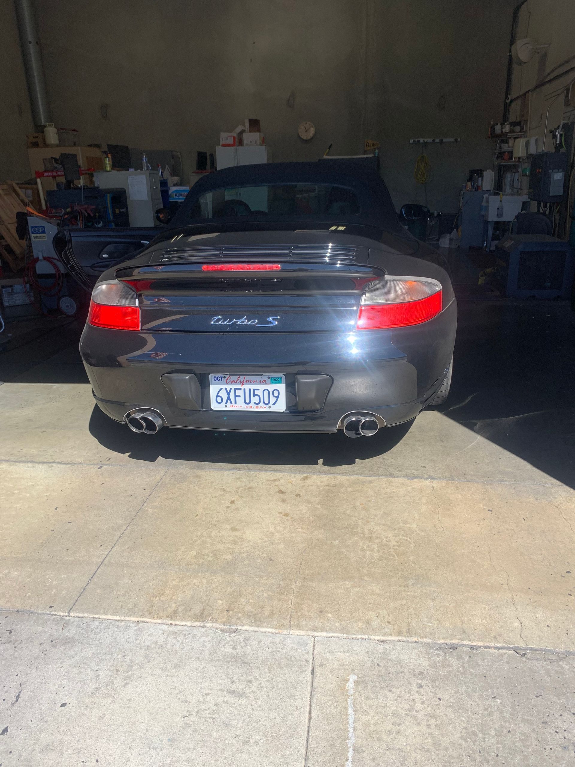 Dark gray Porsche convertible backed into a garage. California license plate visible.