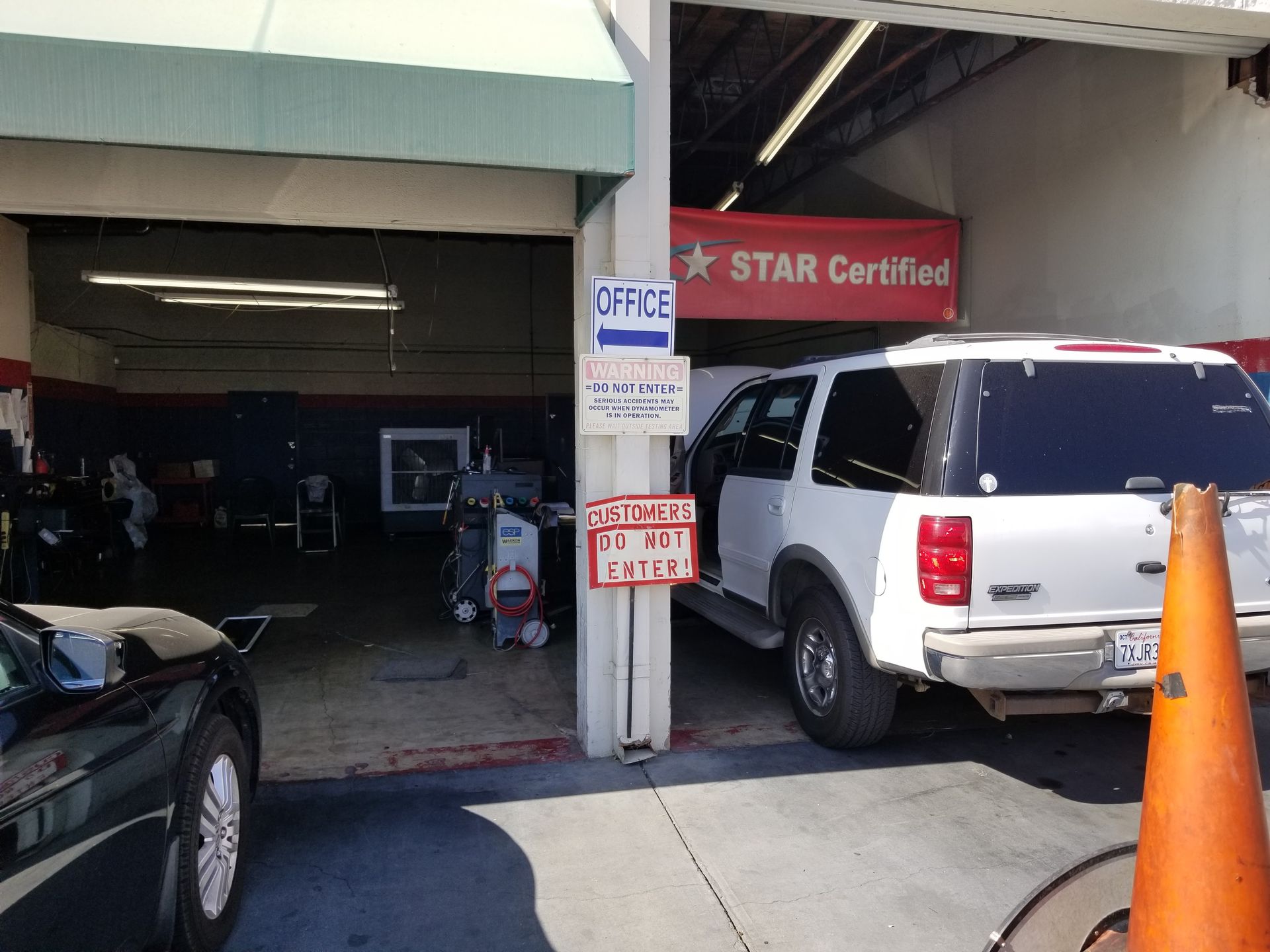 Exterior of auto repair shop: white SUV and black car. 