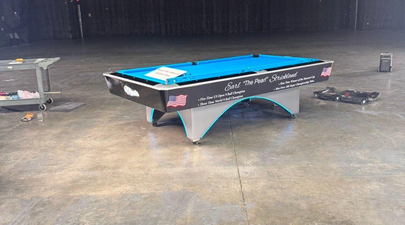 A pool table is sitting on a concrete floor in an empty room.