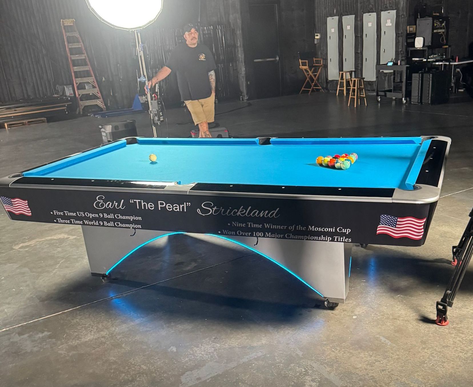 A man standing next to a pool table that says ball time pool