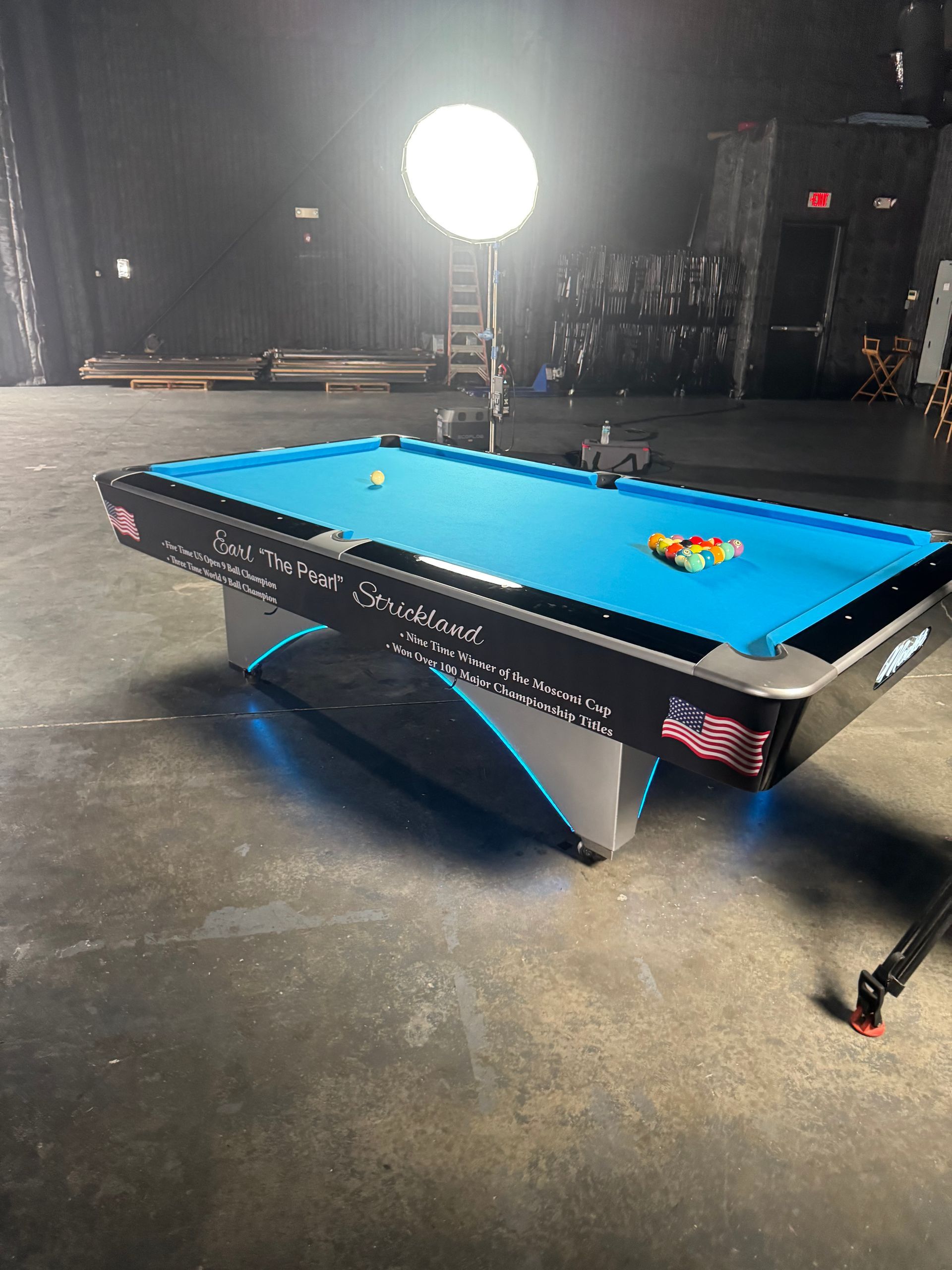 A pool table is sitting on a concrete floor in a dark room.