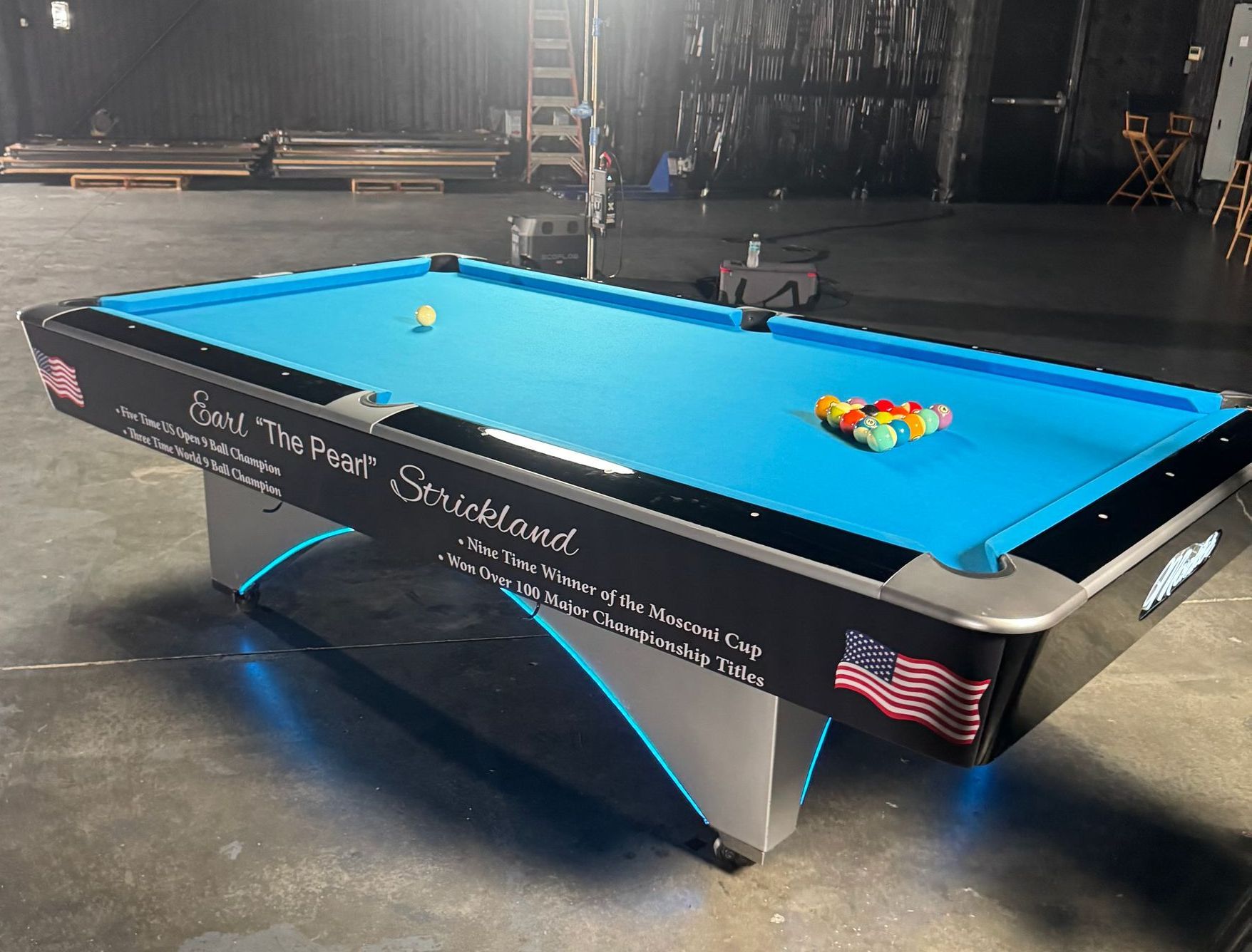 A pool table with a blue cloth and american flag on it