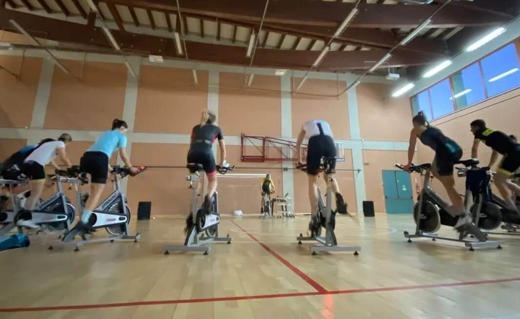 Un gruppo di persone sta pedalando su cyclette in una palestra.