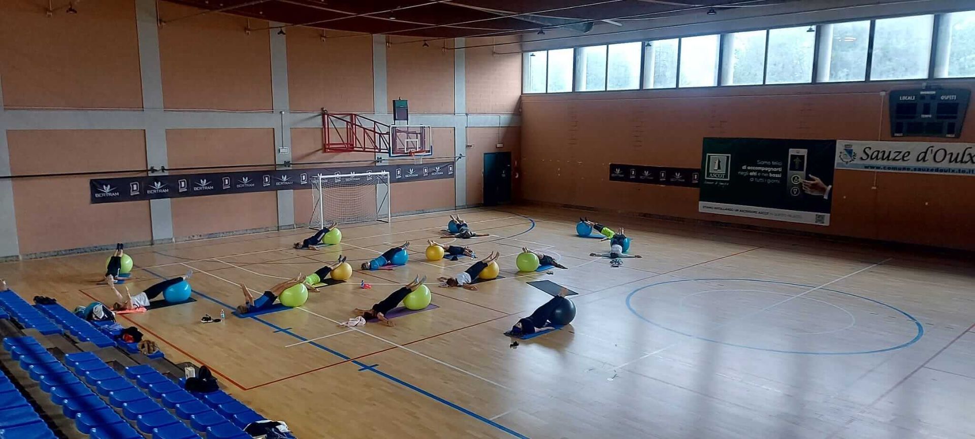 Un gruppo di persone sta facendo esercizi su un pavimento di legno in una palestra.