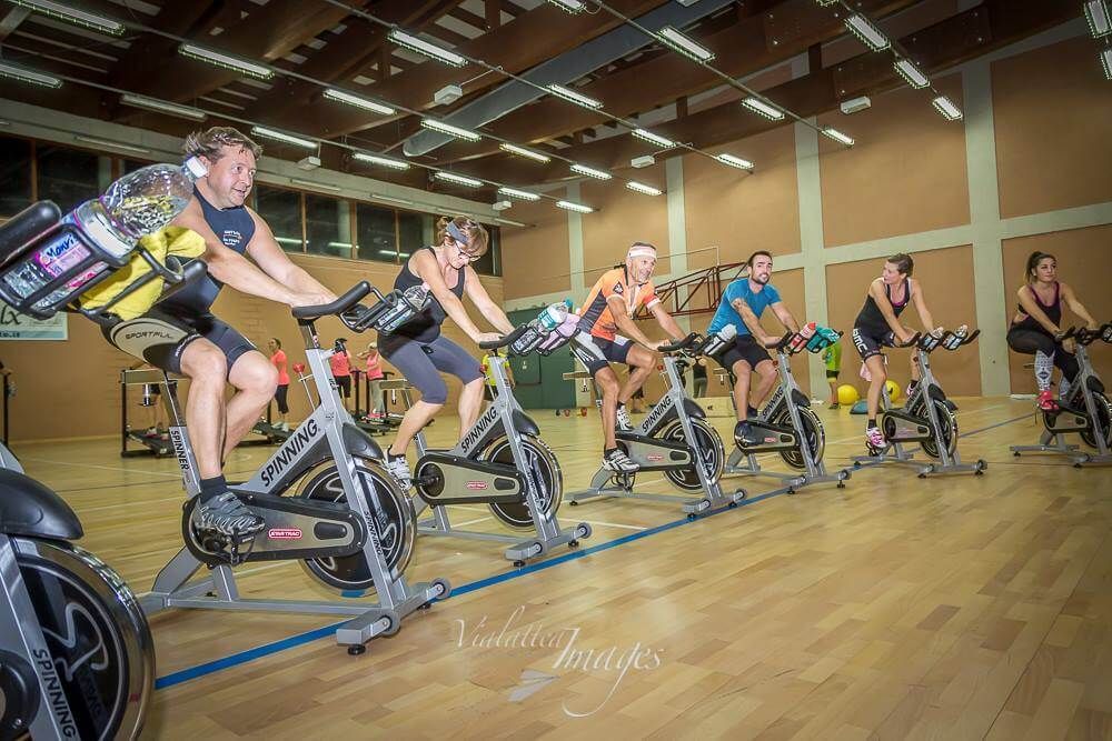 Un gruppo di persone sta pedalando su cyclette in una palestra.